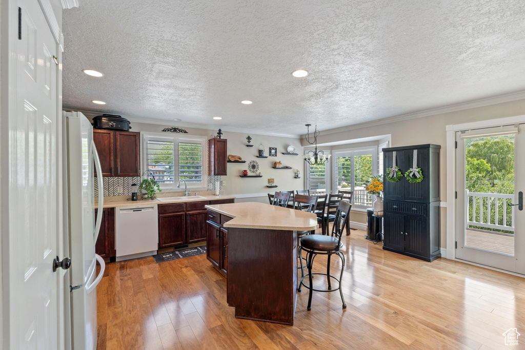 Kitchen with white appliances, a sink, a center island, light countertops, and a kitchen bar