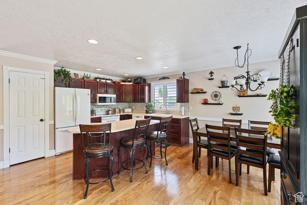 Kitchen with freestanding refrigerator, a textured ceiling, light countertops, crown molding, and a chandelier