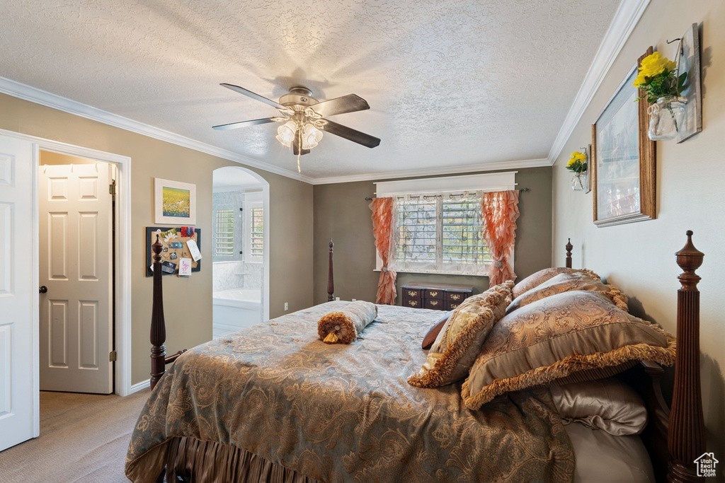 Bedroom with light colored carpet, arched walkways, a textured ceiling, crown molding, and a ceiling fan
