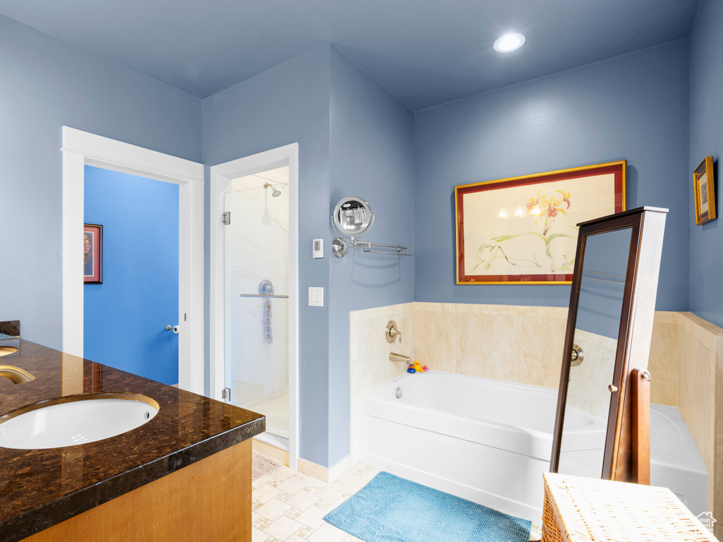 Full bathroom featuring a garden tub, a stall shower, double vanity, and baseboards