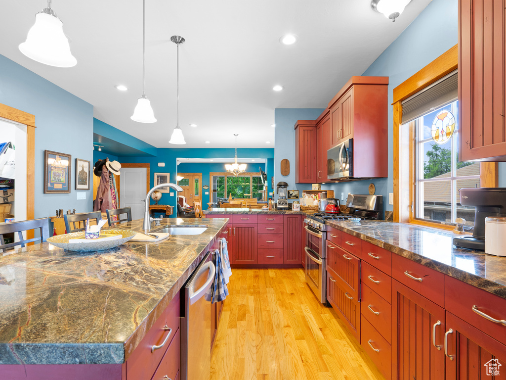 Kitchen featuring stainless steel appliances, a sink, light wood-type flooring, recessed lighting, and pendant lighting