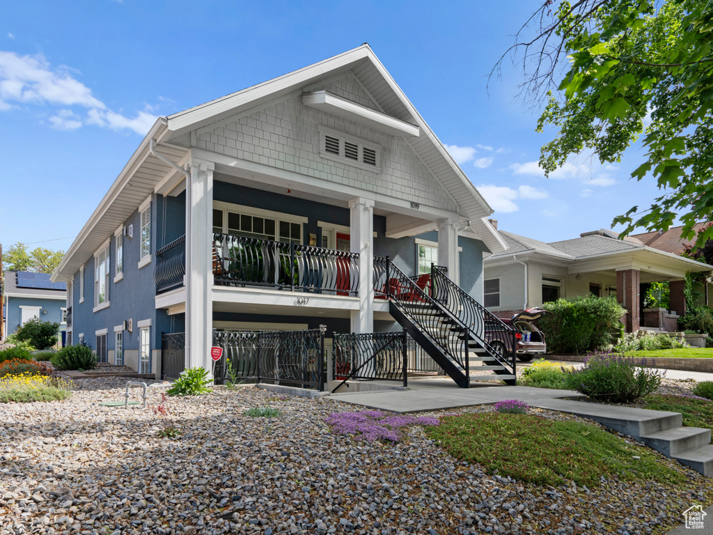 View of front of house with stairs, stucco siding, and covered porch
