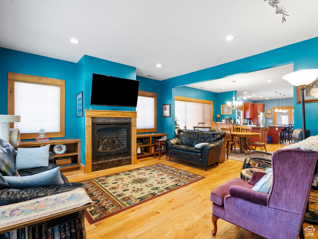 Living room with wood finished floors, a fireplace, a chandelier, and recessed lighting