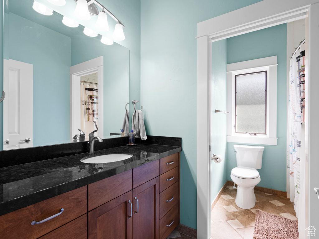 Full bath with vanity, toilet, and baseboards