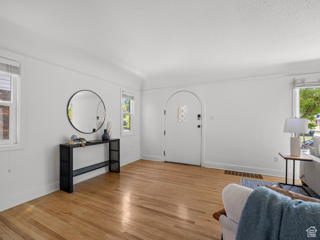 Living area featuring healthy amount of natural light, light wood-type flooring, and a textured ceiling