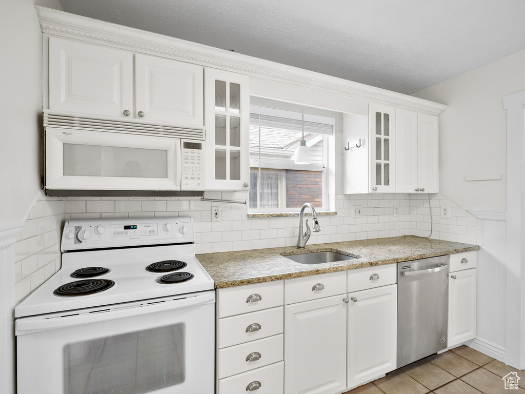 Kitchen featuring white cabinets, glass insert cabinets, a sink, and white appliances