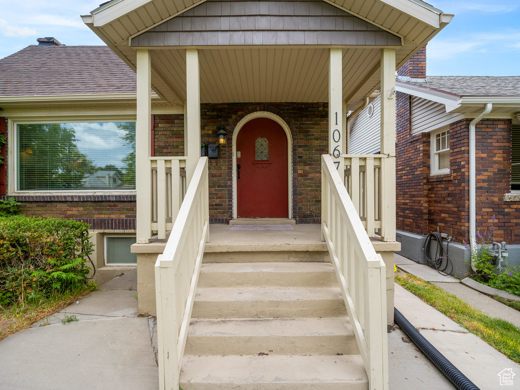 View of exterior entry featuring brick siding and roof with shingles