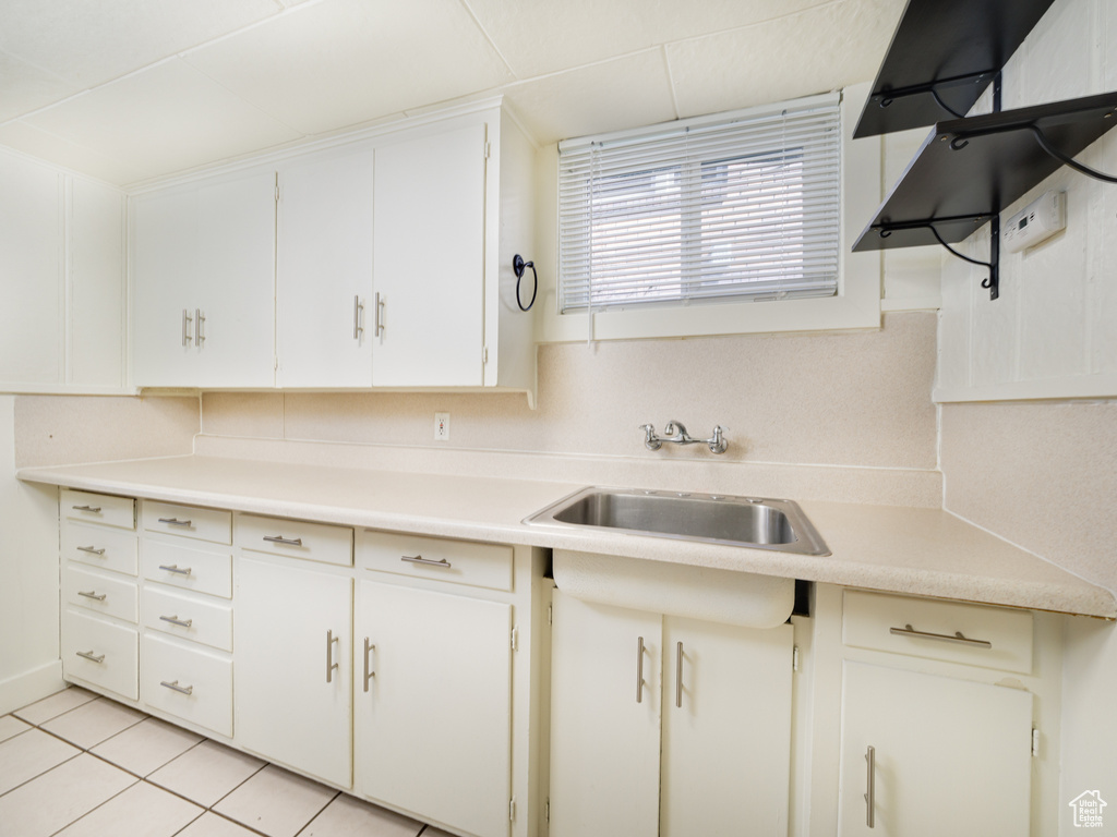 Kitchen featuring a sink, light countertops, light tile patterned flooring, and white cabinetry