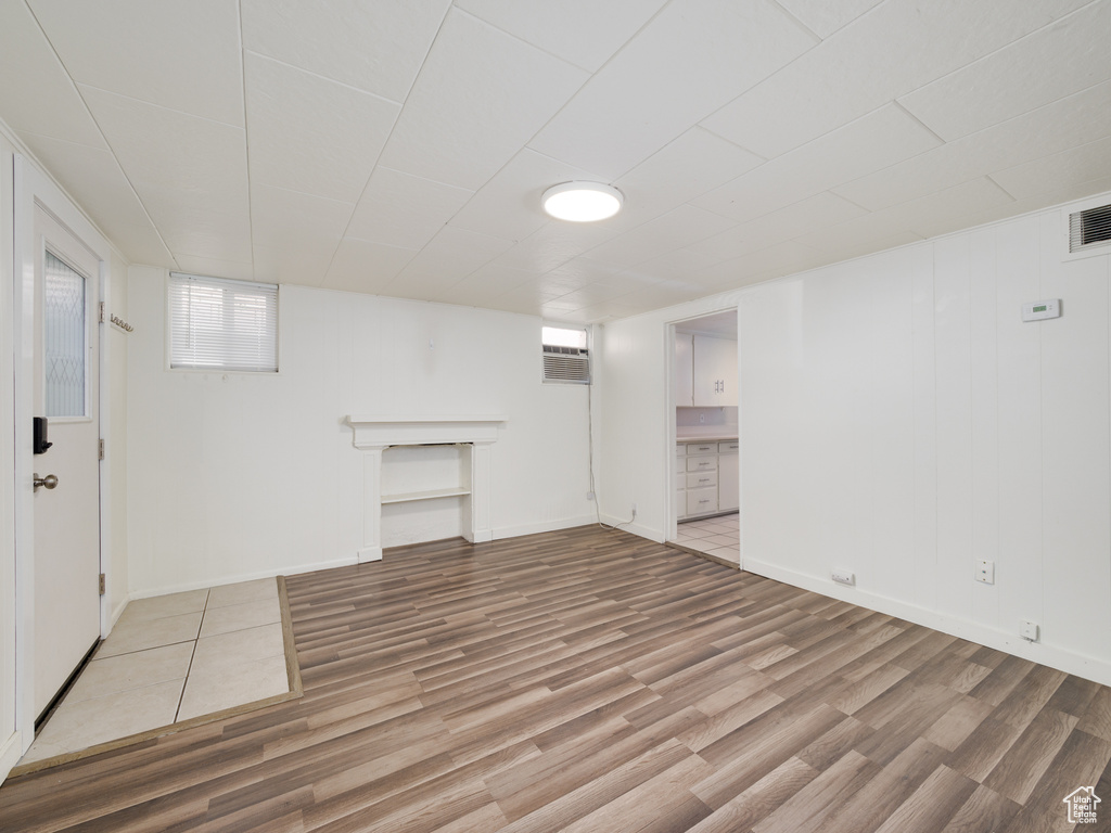 Below grade area featuring light wood-style floors, an AC wall unit, and baseboards