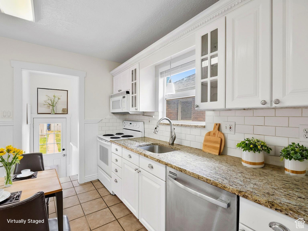 Kitchen with white appliances, a sink, glass insert cabinets, white cabinetry, and backsplash