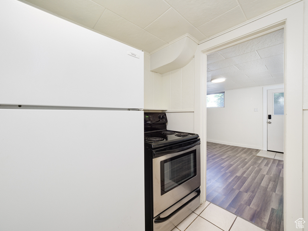 Kitchen with freestanding refrigerator, stainless steel electric range oven, and wood finished floors