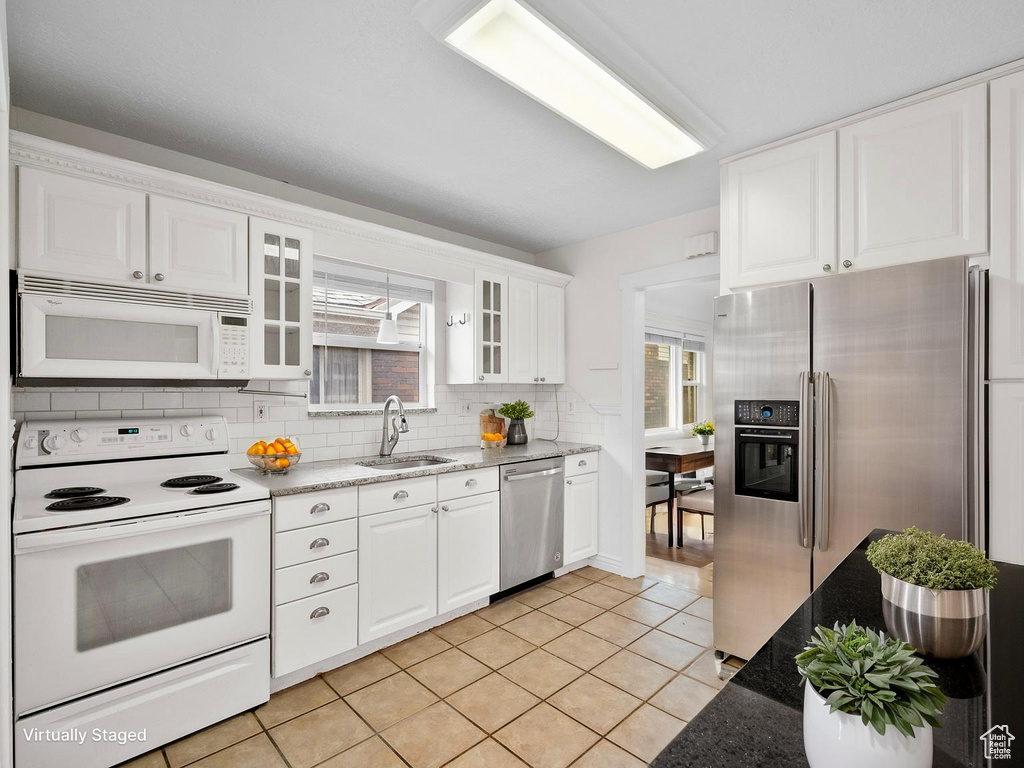Kitchen featuring appliances with stainless steel finishes, a sink, healthy amount of natural light, and tasteful backsplash