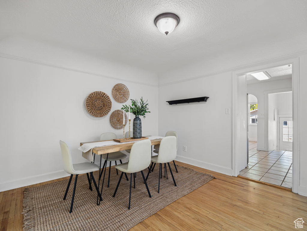 Dining area featuring wood finished floors, arched walkways, and a textured ceiling