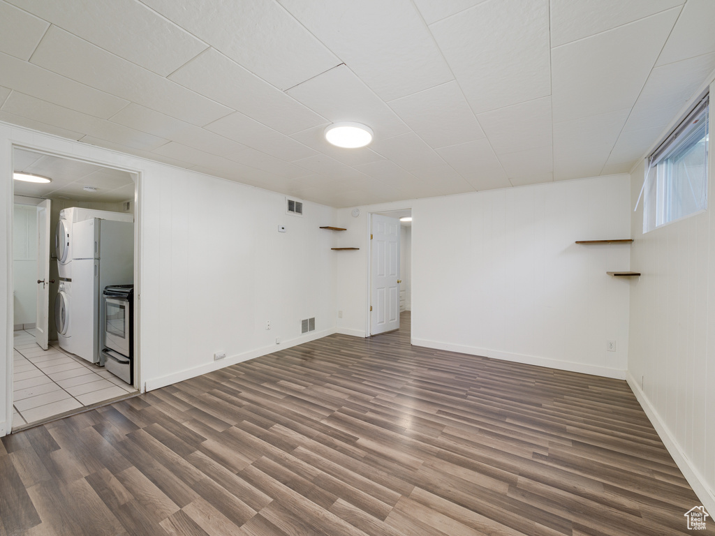 Spare room featuring stacked washer / drying machine, wood finished floors, and baseboards
