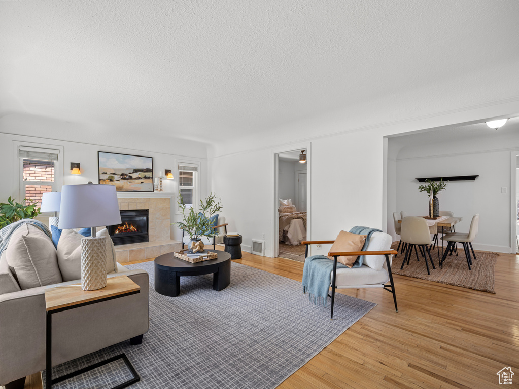 Living room featuring a textured ceiling, light wood finished floors, and a fireplace