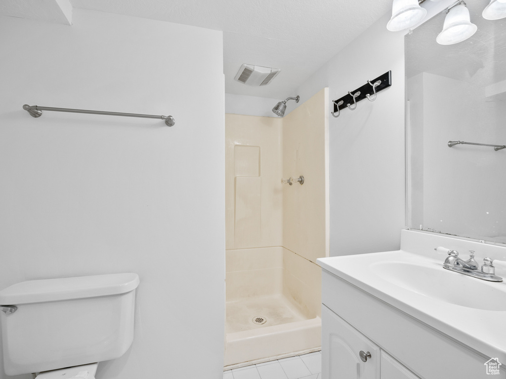 Bathroom with a shower stall, vanity, tile patterned flooring, and toilet