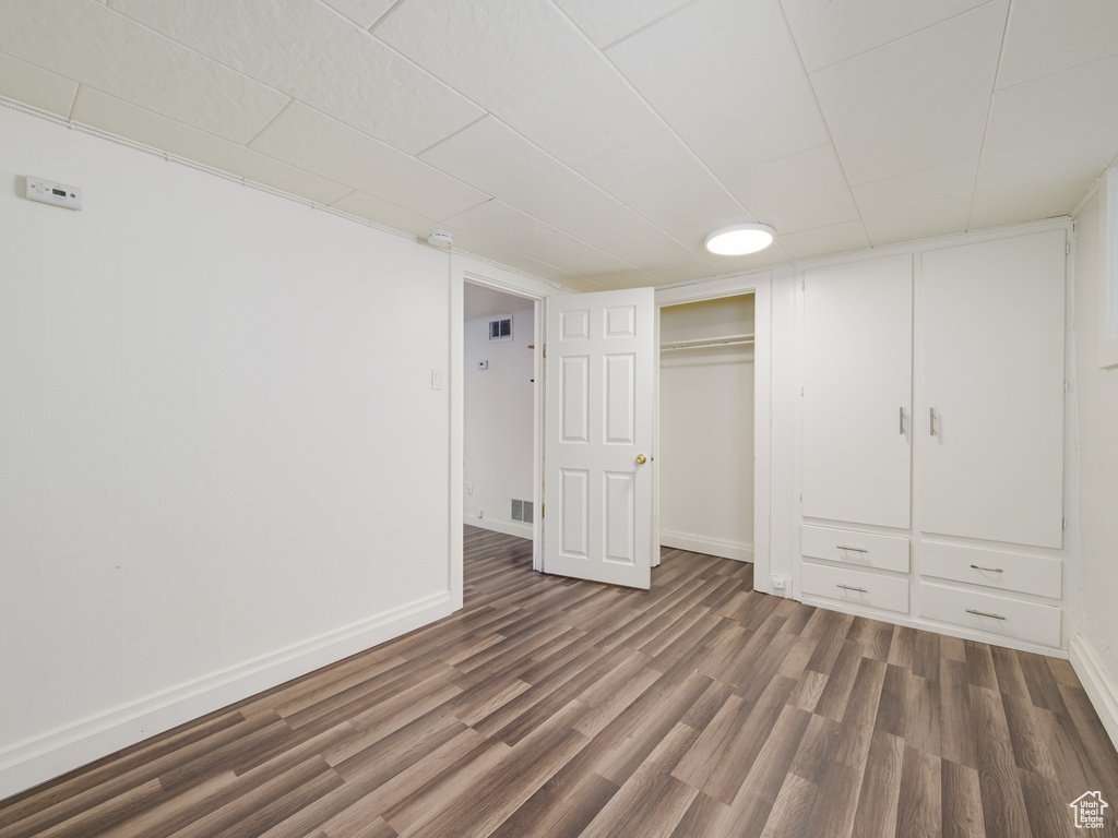 Unfurnished bedroom featuring wood finished floors, baseboards, and a closet