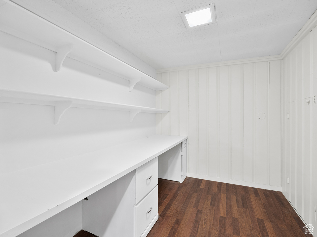 Unfurnished office featuring built in desk and dark wood-style floors
