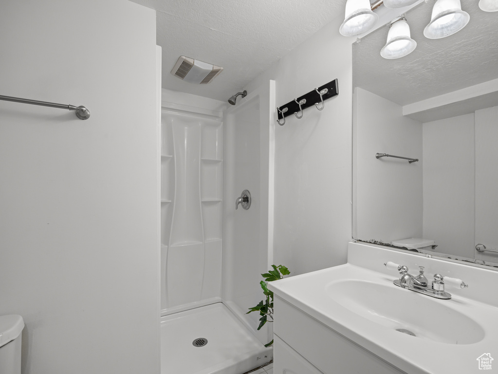 Bathroom featuring a stall shower, vanity, and a textured ceiling