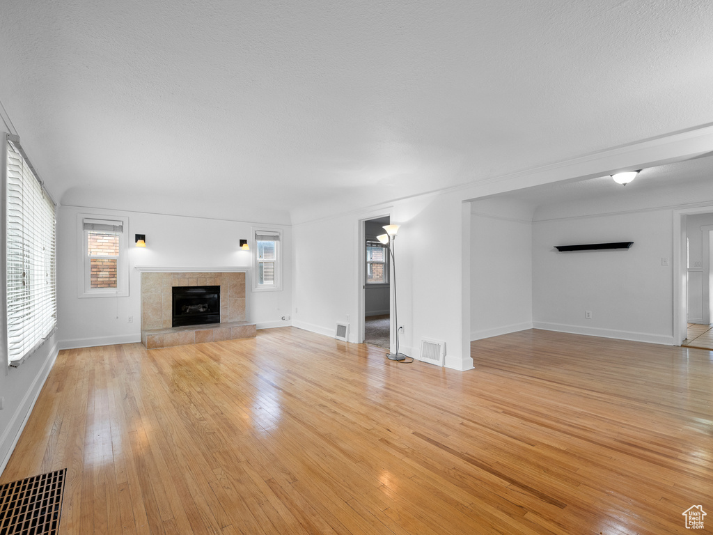 Unfurnished living room with light wood-type flooring, a fireplace, and baseboards