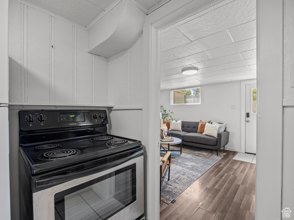 Kitchen featuring stainless steel range with electric cooktop, wood finished floors, and white cabinets