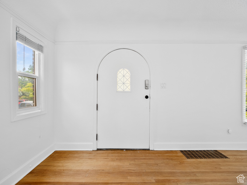 Foyer with light wood finished floors, baseboards, and arched walkways