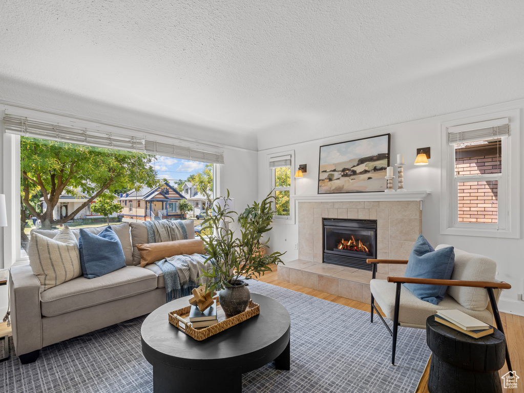 Living room featuring a tile fireplace, a textured ceiling, and wood finished floors