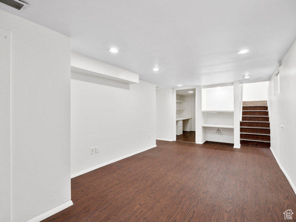 Finished below grade area with baseboards, dark wood finished floors, recessed lighting, and stairs