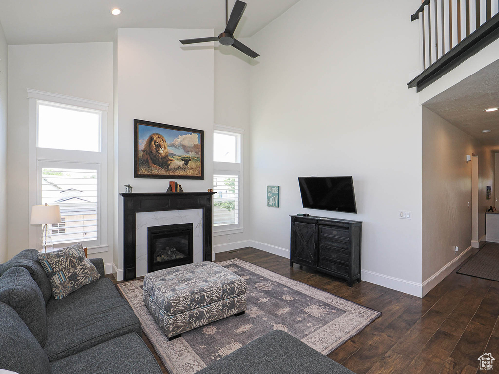 Living room with high vaulted ceiling, dark wood-style floors, baseboards, ceiling fan, and a premium fireplace