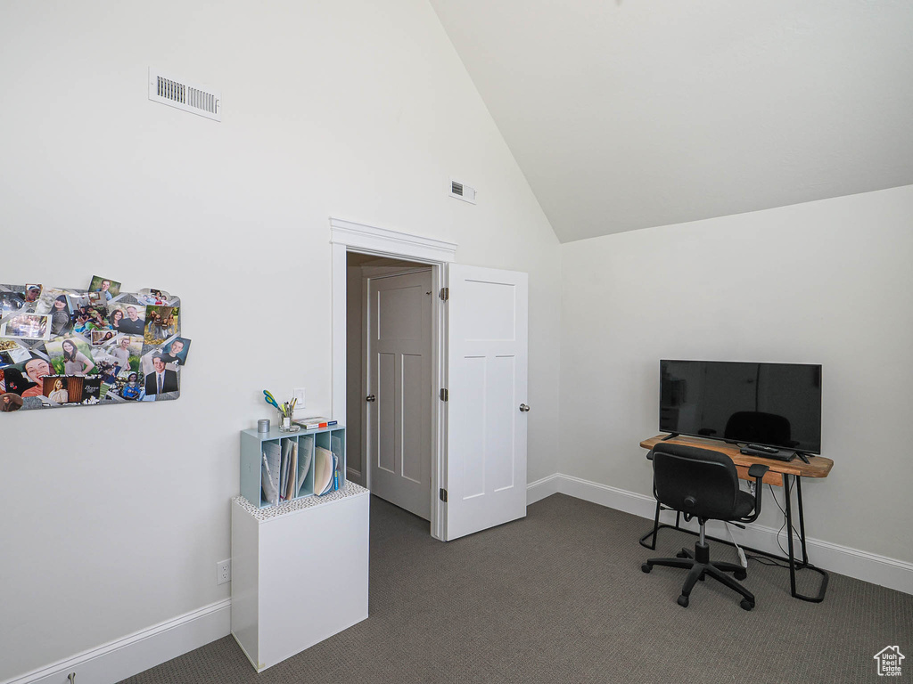 Office space with dark colored carpet, high vaulted ceiling, and baseboards