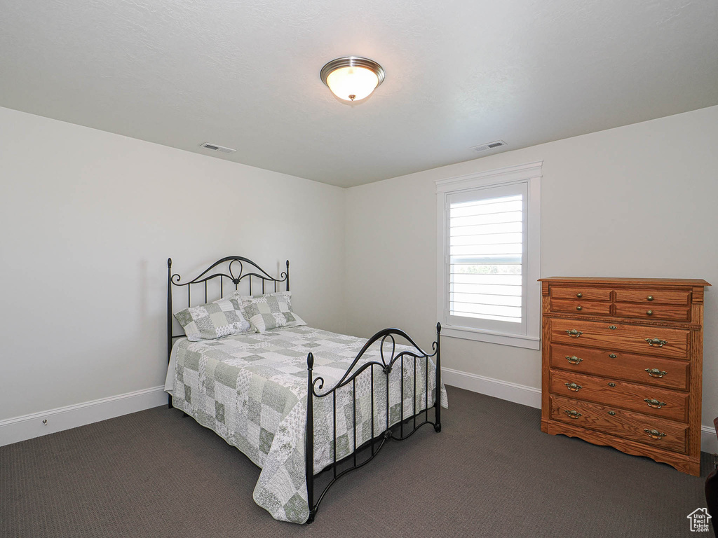 Bedroom featuring dark carpet and baseboards