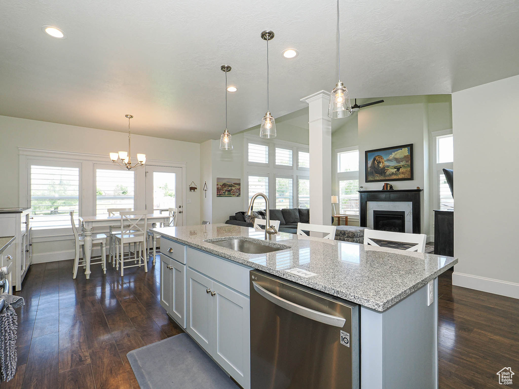 Kitchen with stainless steel dishwasher, a sink, baseboards, a chandelier, and recessed lighting