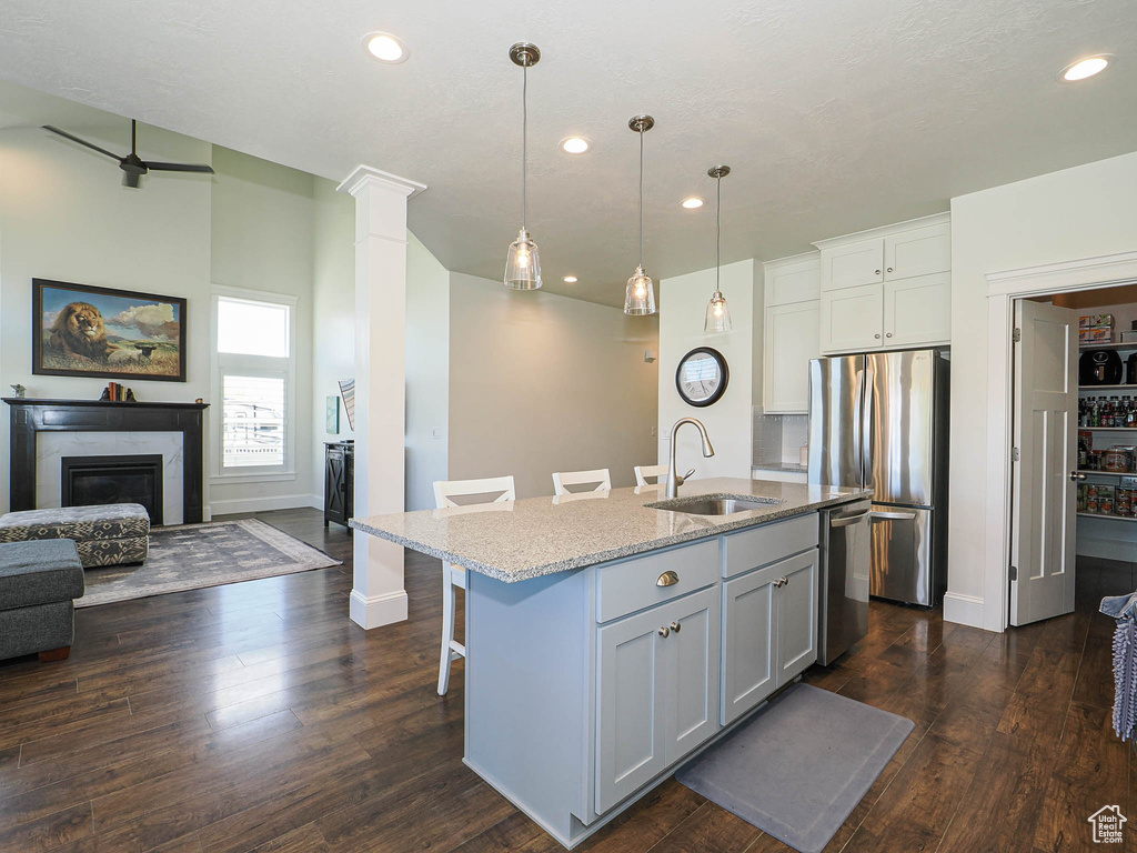 Kitchen featuring a sink, appliances with stainless steel finishes, open floor plan, light stone counters, and a kitchen breakfast bar