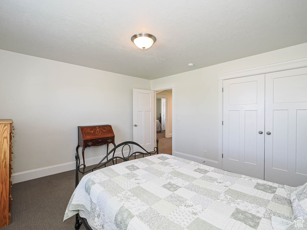 Bedroom featuring dark carpet, baseboards, and a closet