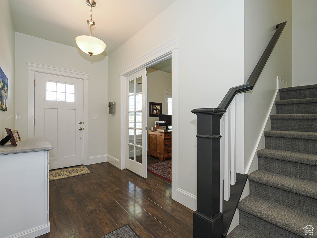 Entrance foyer with dark wood-style floors, stairway, and baseboards