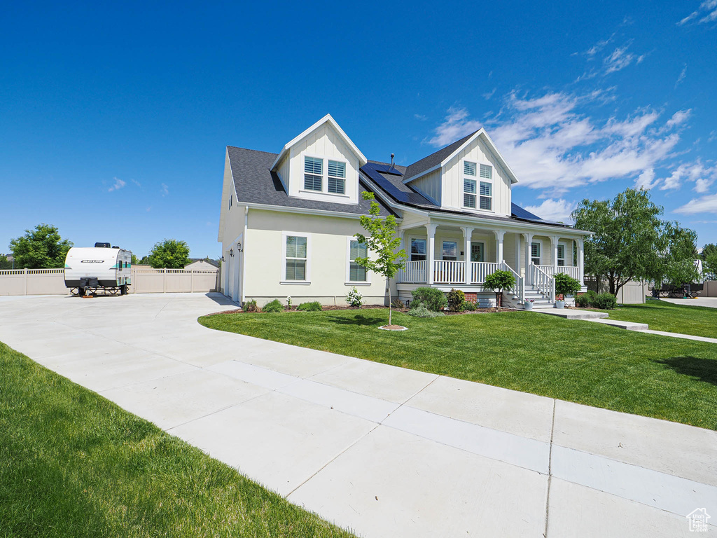 View of front of property featuring covered porch, solar panels, concrete driveway, and a garage