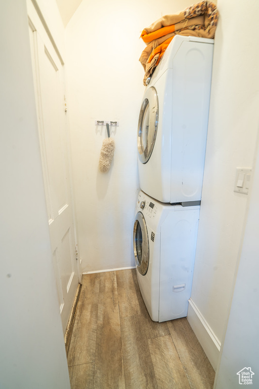 Washroom with estacked washer and dryer, baseboards, and wood finished floors