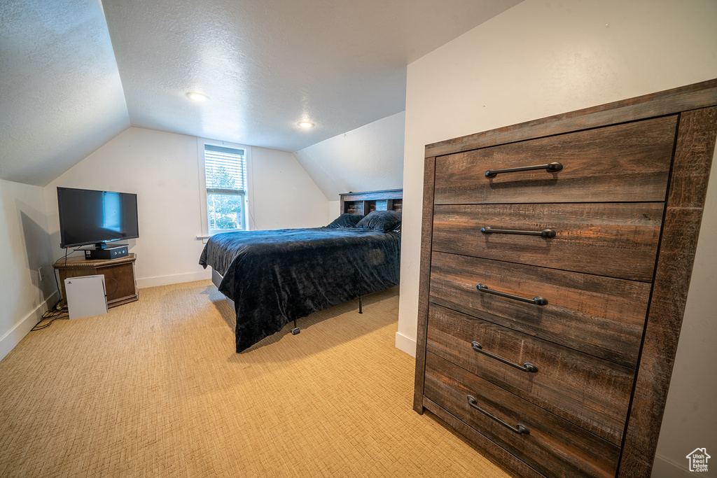 Bedroom featuring lofted ceiling, light colored carpet, and baseboards