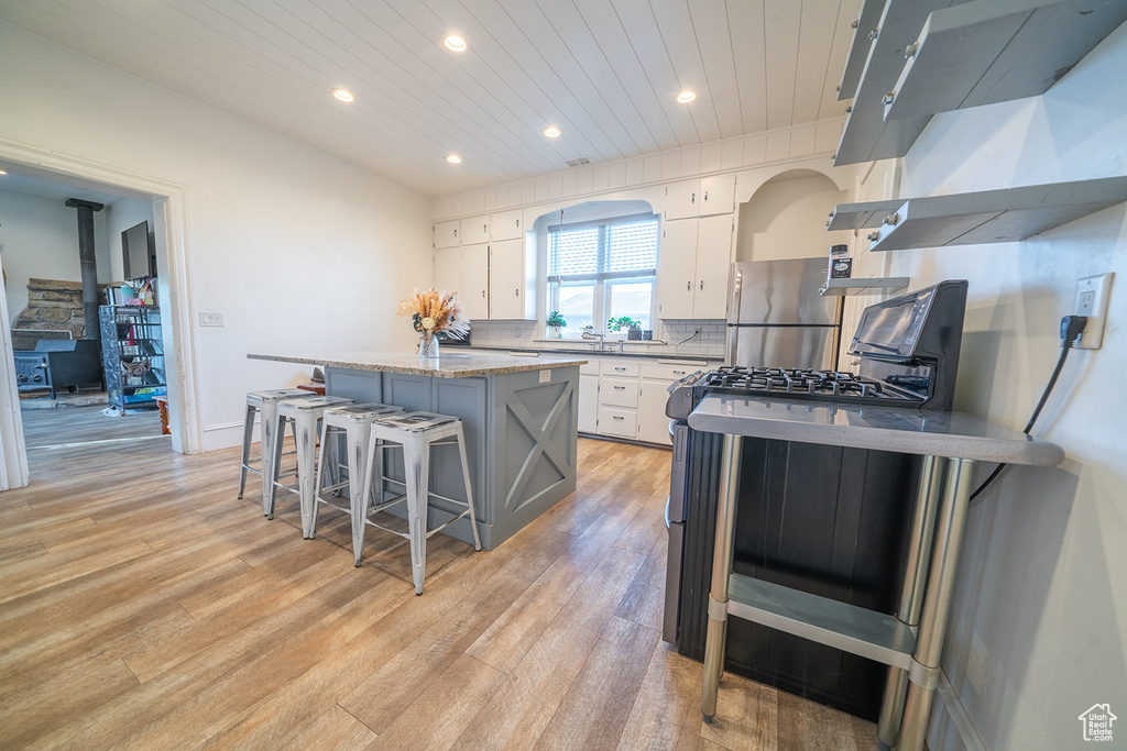 Kitchen with appliances with stainless steel finishes, recessed lighting, a center island, white cabinetry, and light wood finished floors