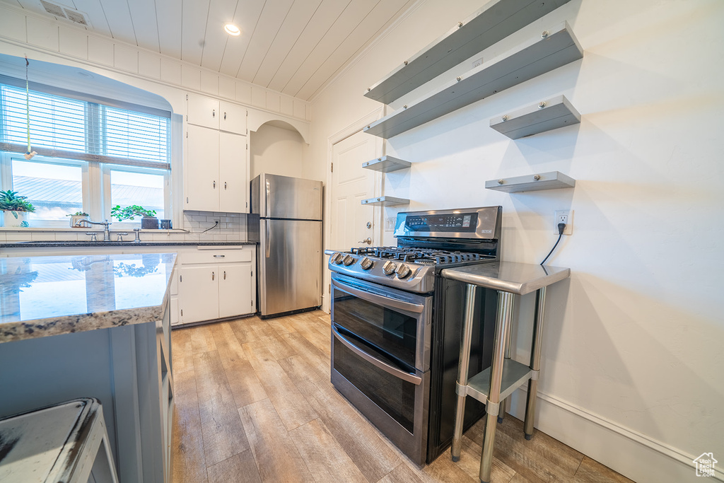 Kitchen featuring stainless steel appliances, open shelves, light wood-style flooring, tasteful backsplash, and recessed lighting