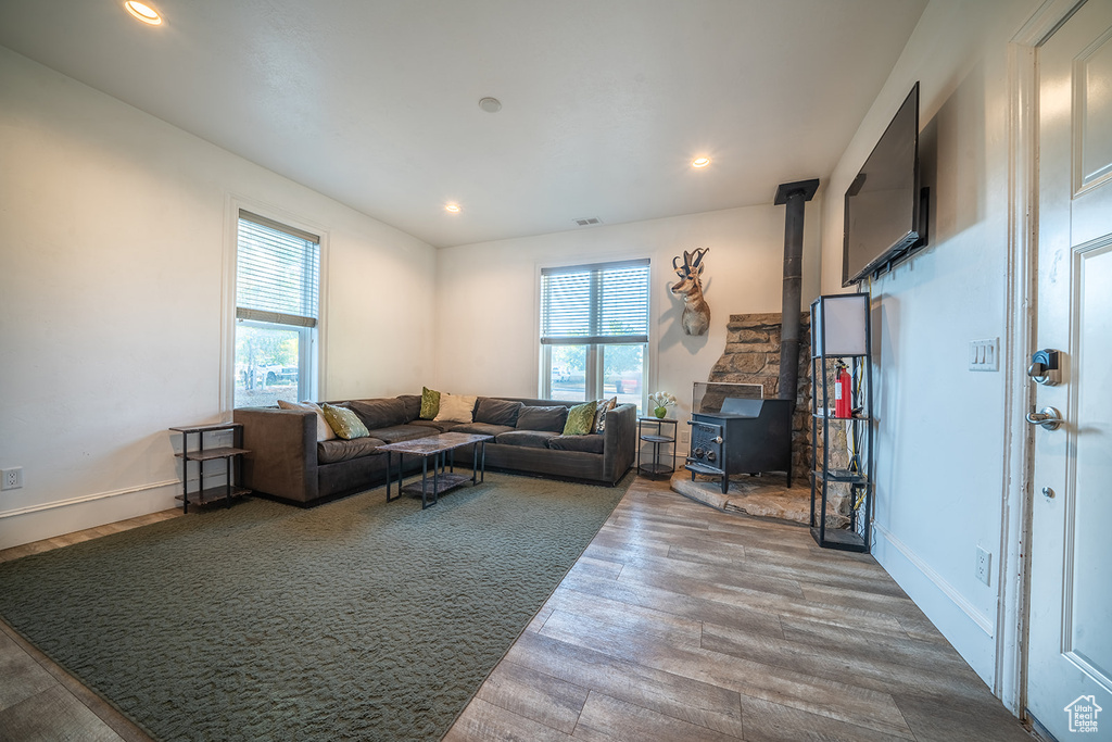 Living area with a wood stove, wood finished floors, recessed lighting, and baseboards