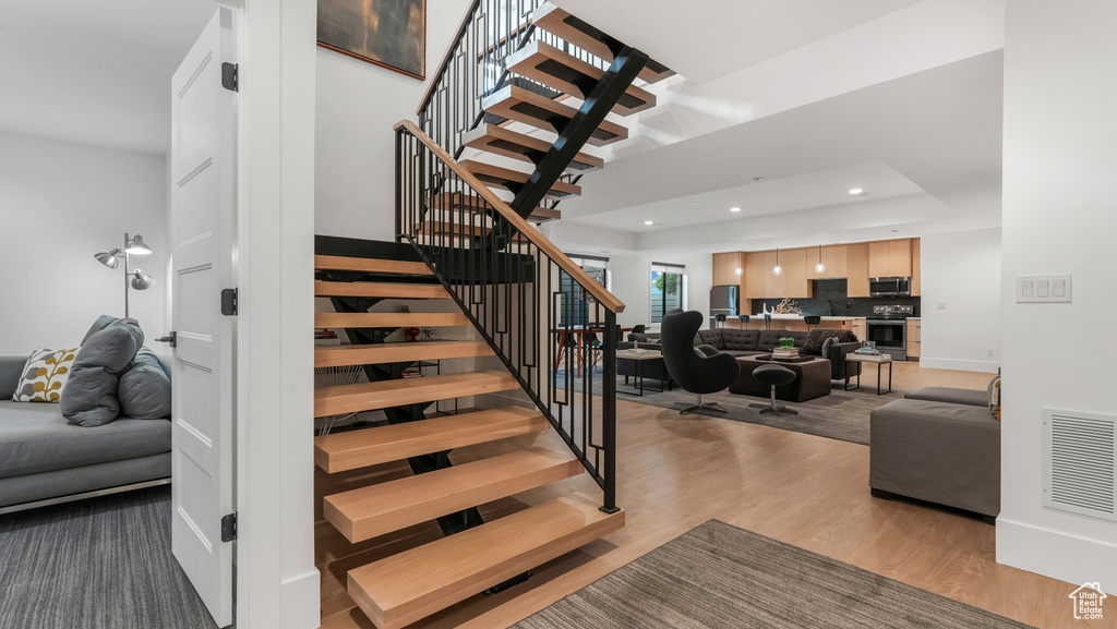 Staircase featuring wood finished floors, recessed lighting, and baseboards