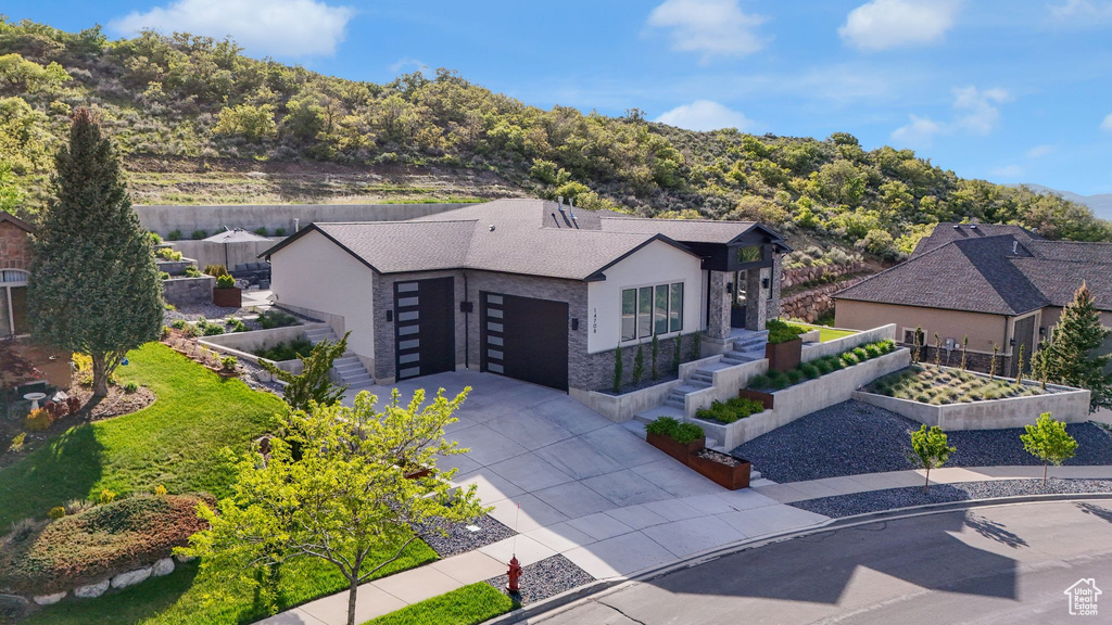 View of front of property featuring driveway, a garden, and an attached garage