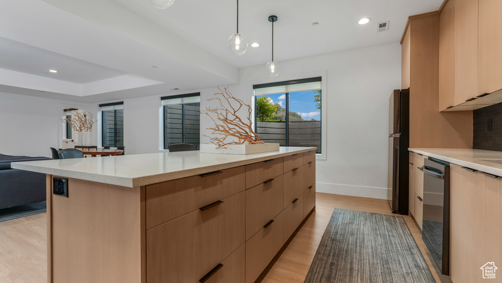 Kitchen with modern cabinets, a kitchen island, light wood finished floors, light brown cabinetry, and dishwashing machine