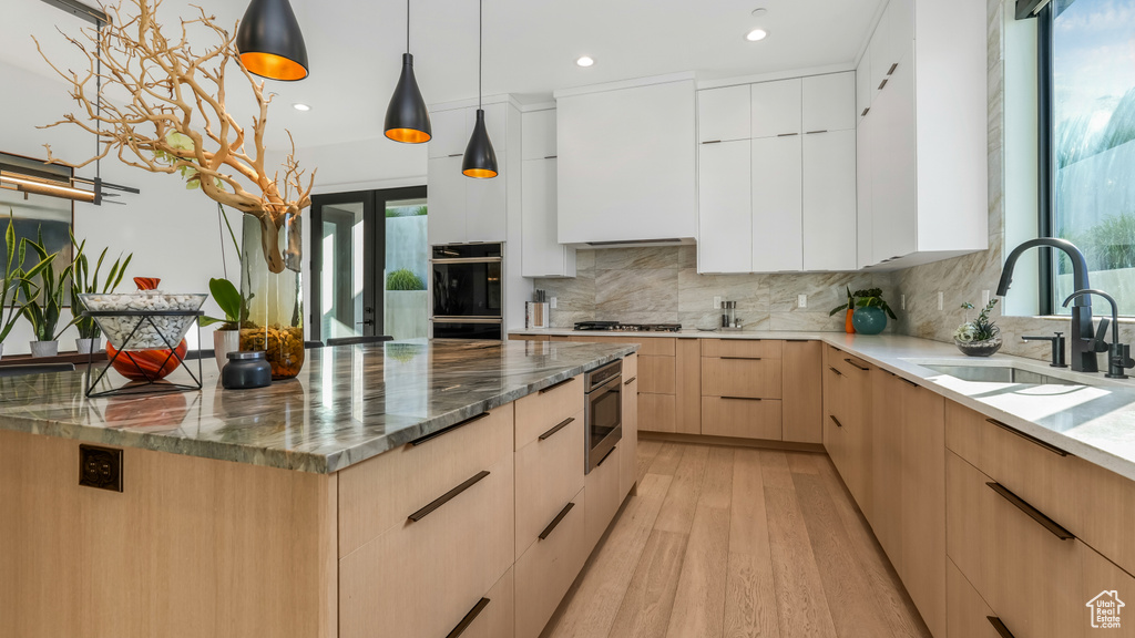 Kitchen with modern cabinets, a sink, light brown cabinets, plenty of natural light, and recessed lighting