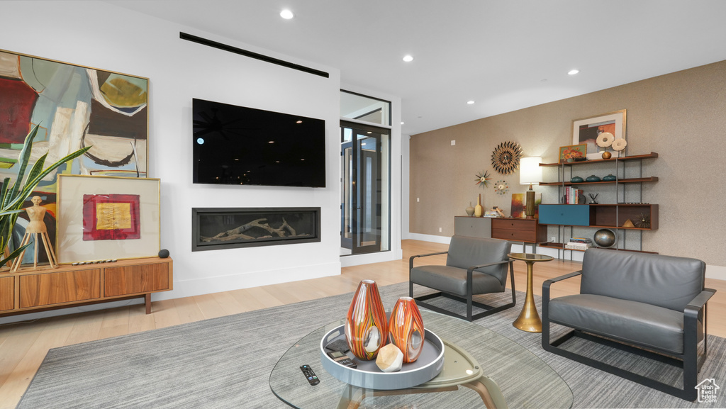 Living room featuring wood finished floors, a glass covered fireplace, and recessed lighting