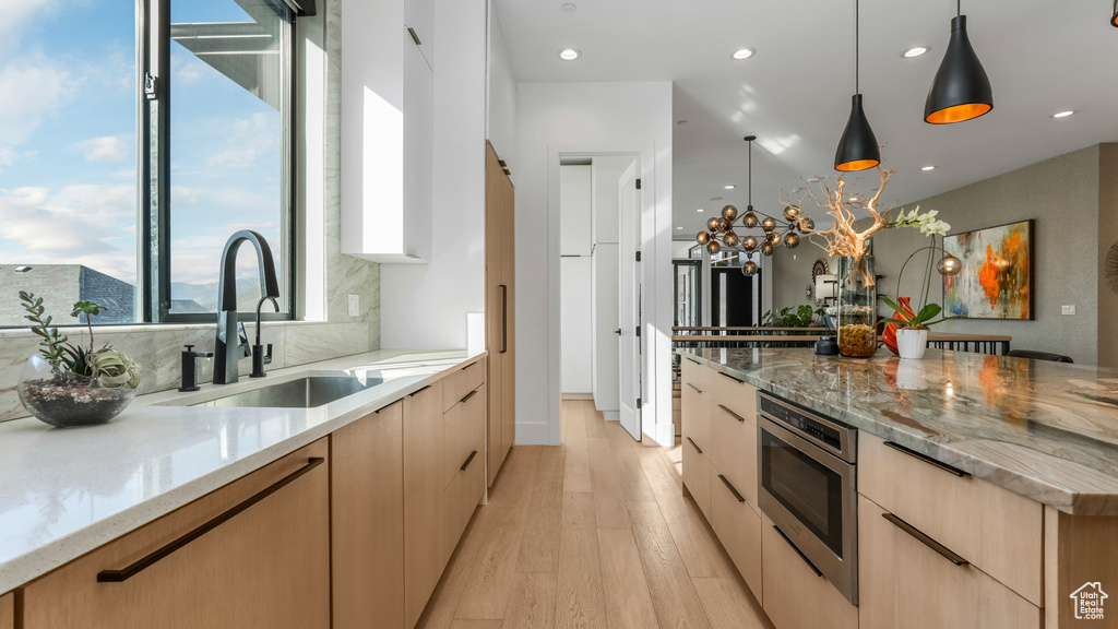 Kitchen featuring modern cabinets, a sink, light brown cabinetry, and recessed lighting