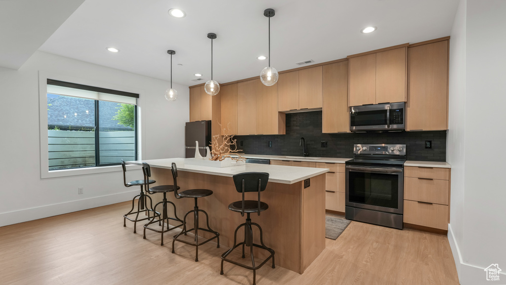Kitchen with appliances with stainless steel finishes, a sink, light wood-style floors, tasteful backsplash, and recessed lighting