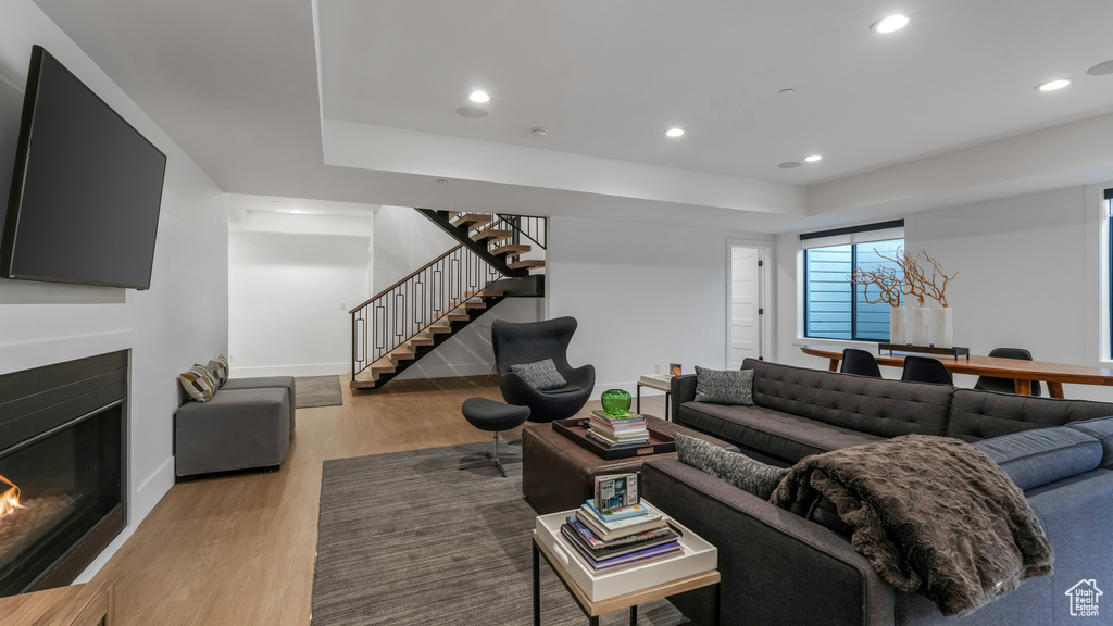Living area with stairs, a glass covered fireplace, recessed lighting, wood finished floors, and baseboards