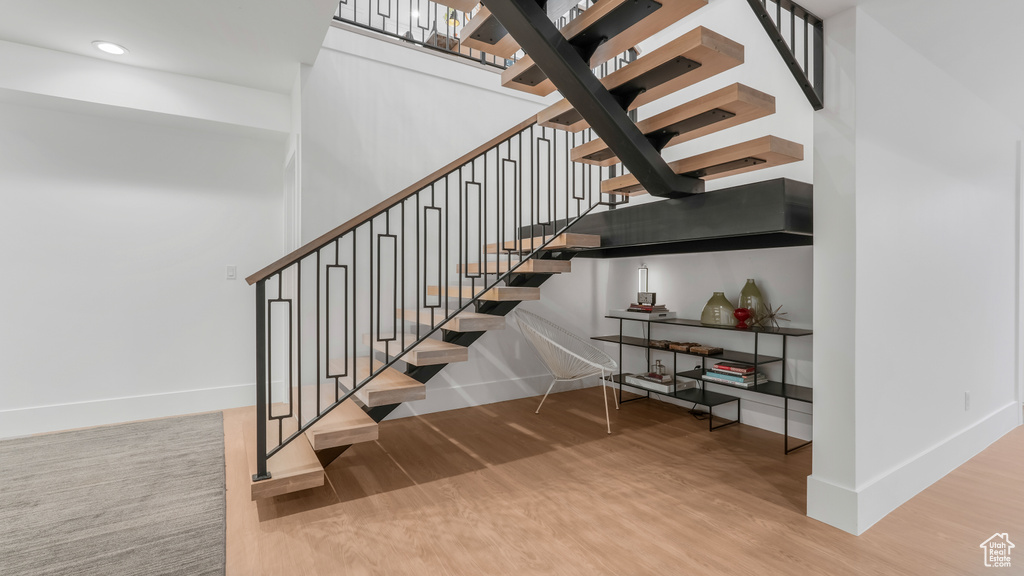 Stairs with baseboards, wood finished floors, and recessed lighting
